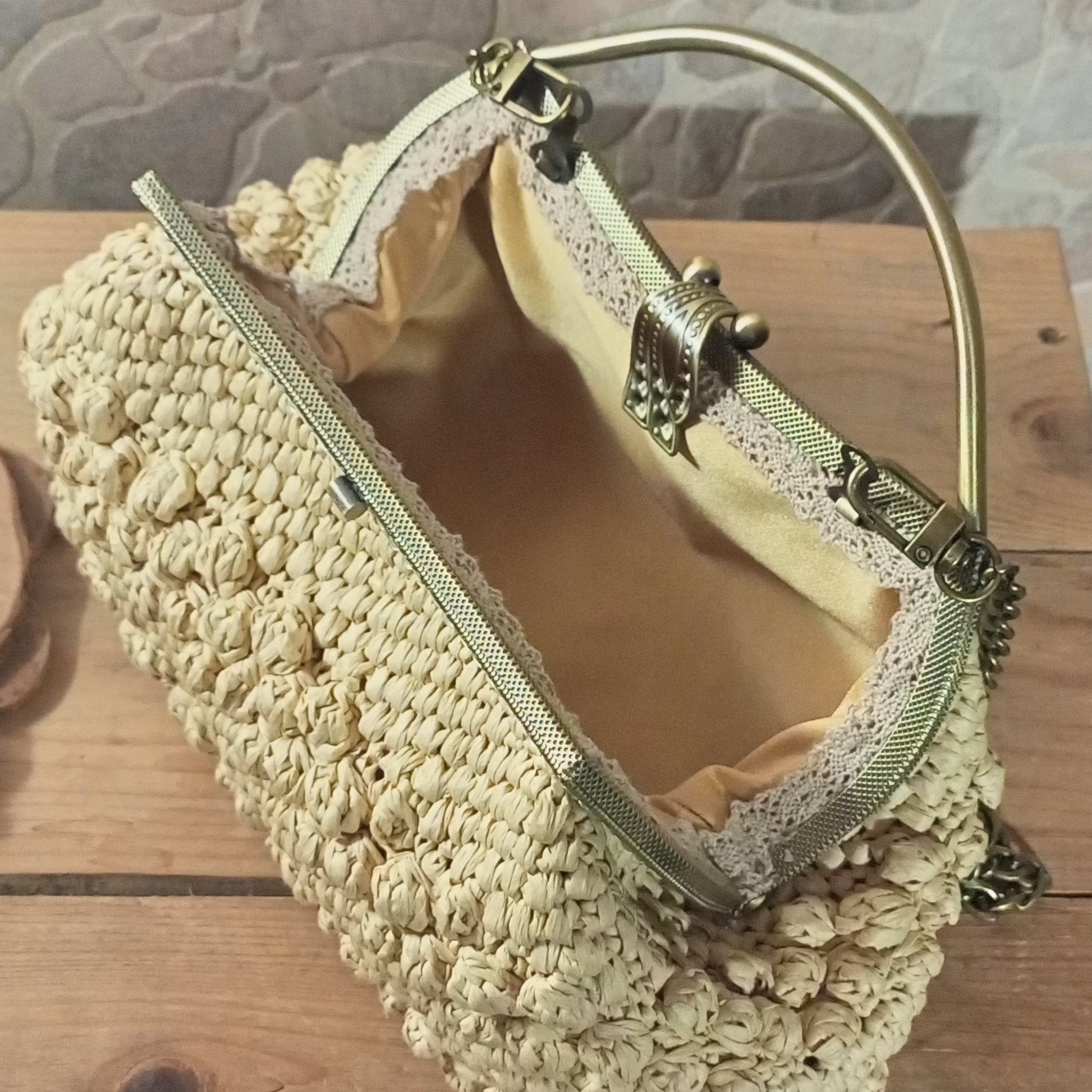 Close-up of gold kisslock clasp on beige crochet bag