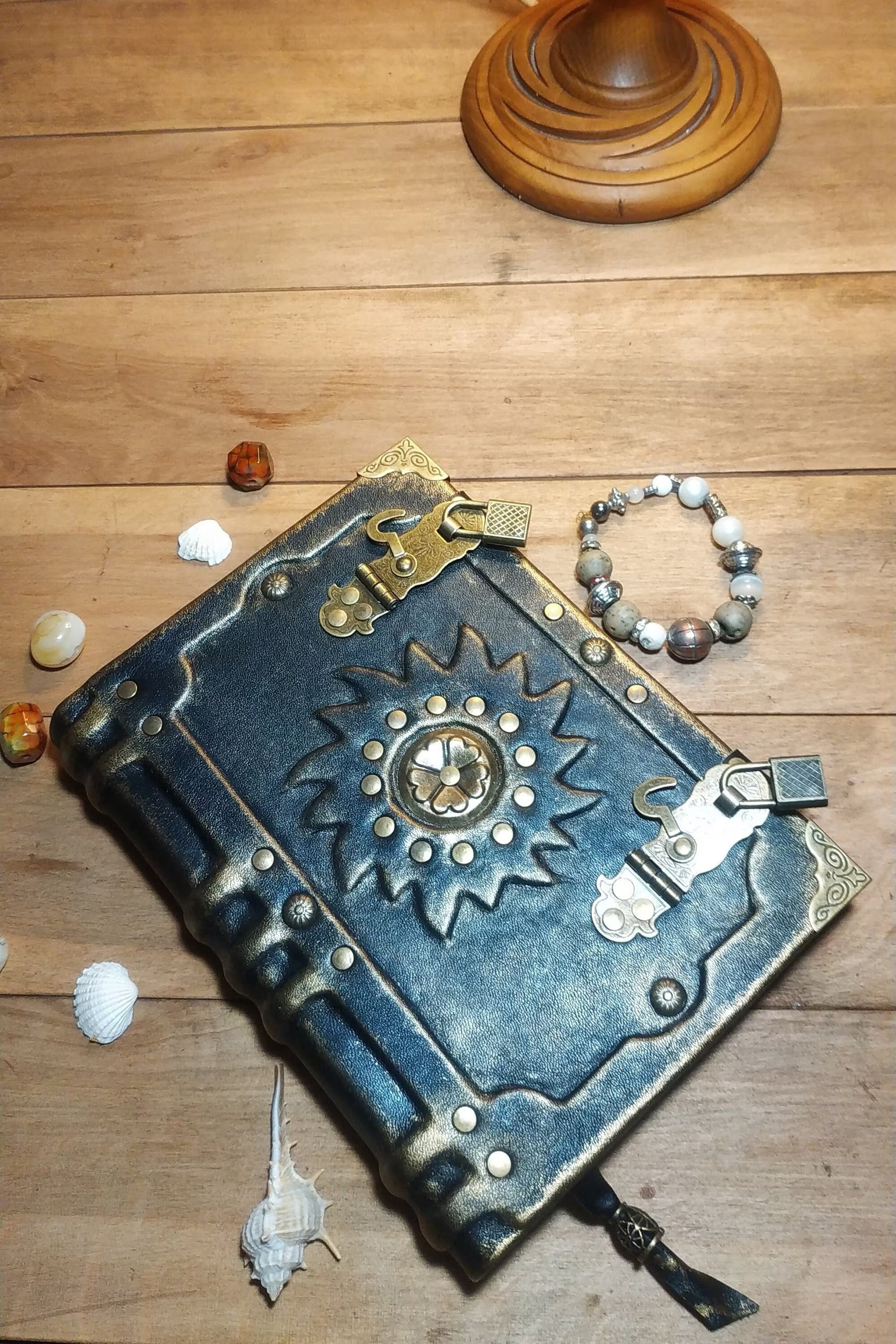 Decorative aged  black leather-bound book with metallic embellishments on a wooden surface