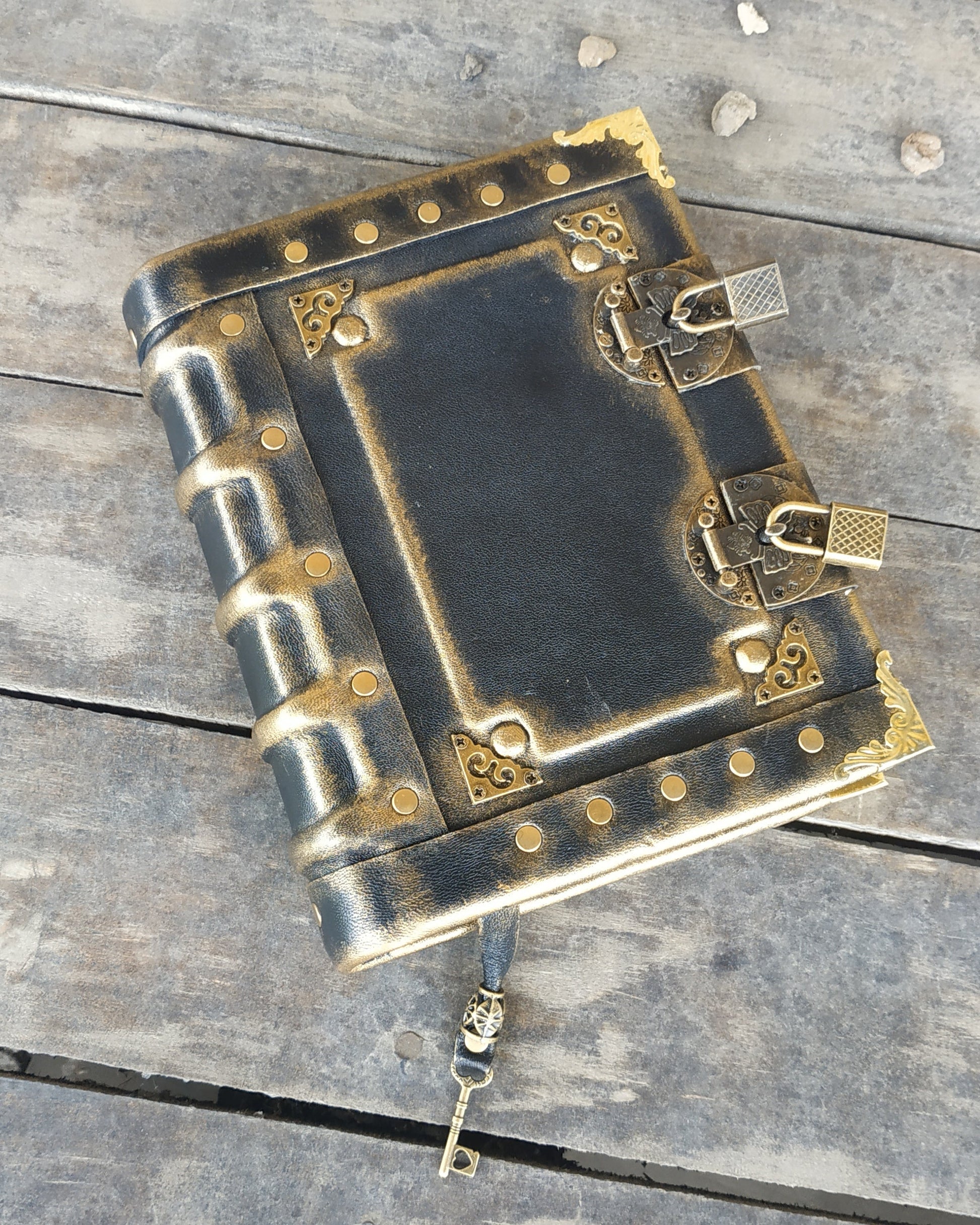 Decorative aged black leather-bound journal with brass  accents on a wooden surface