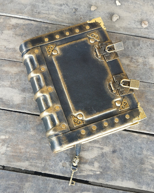 Decorative aged black leather-bound journal with brass  accents on a wooden surface