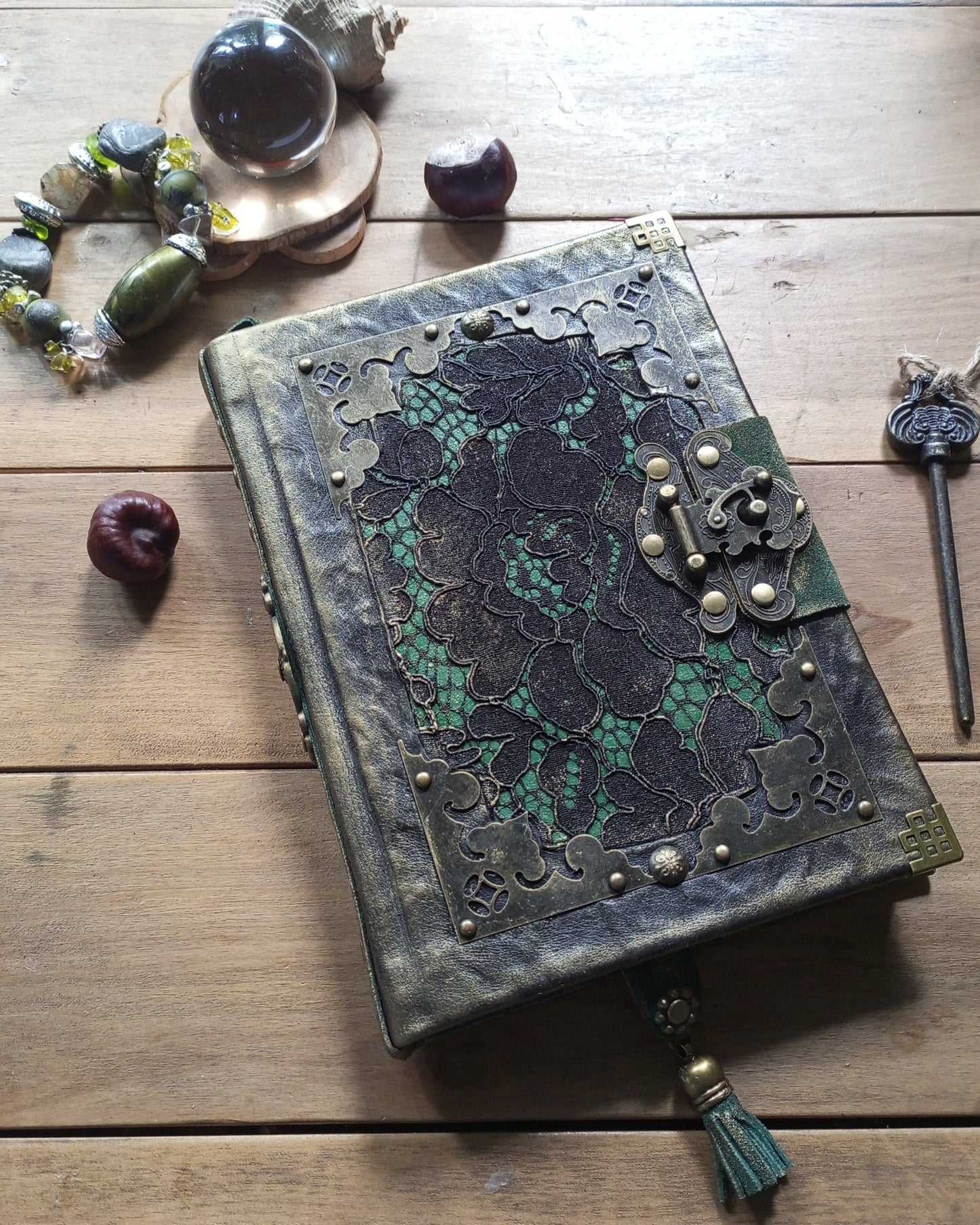 Aged blalck and green leather-bound grimoire with intricate green lace embelishments and brass antique lock 