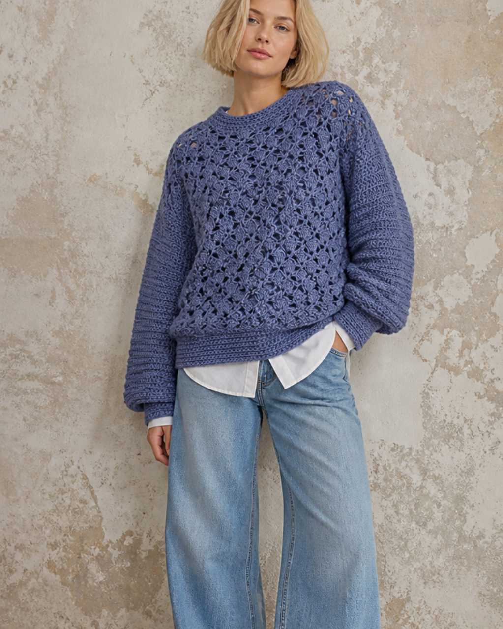 Person wearing a handmade oversize blue crochet sweater and jeans 