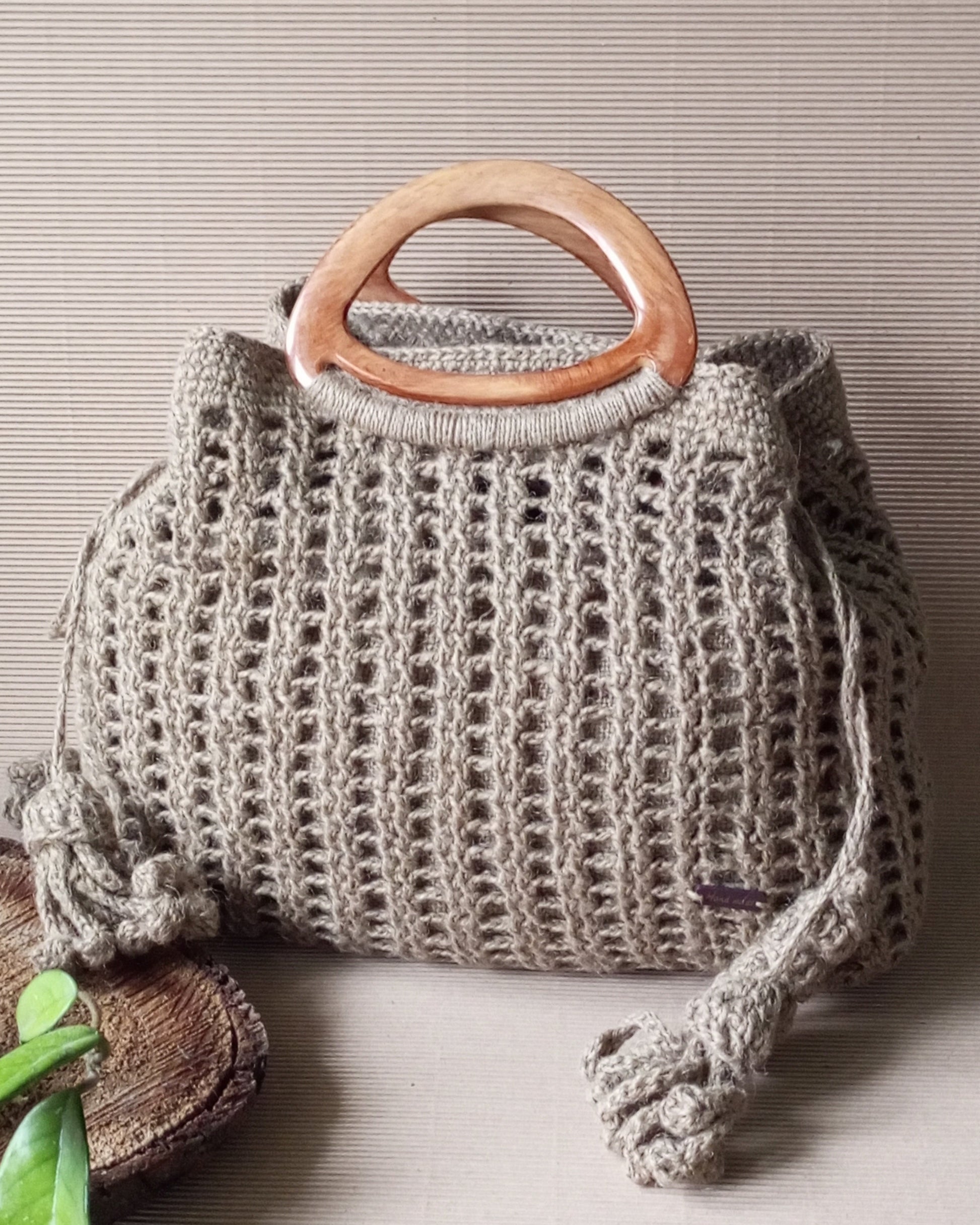 Crocheted handbag with plastic handles on a neutral background