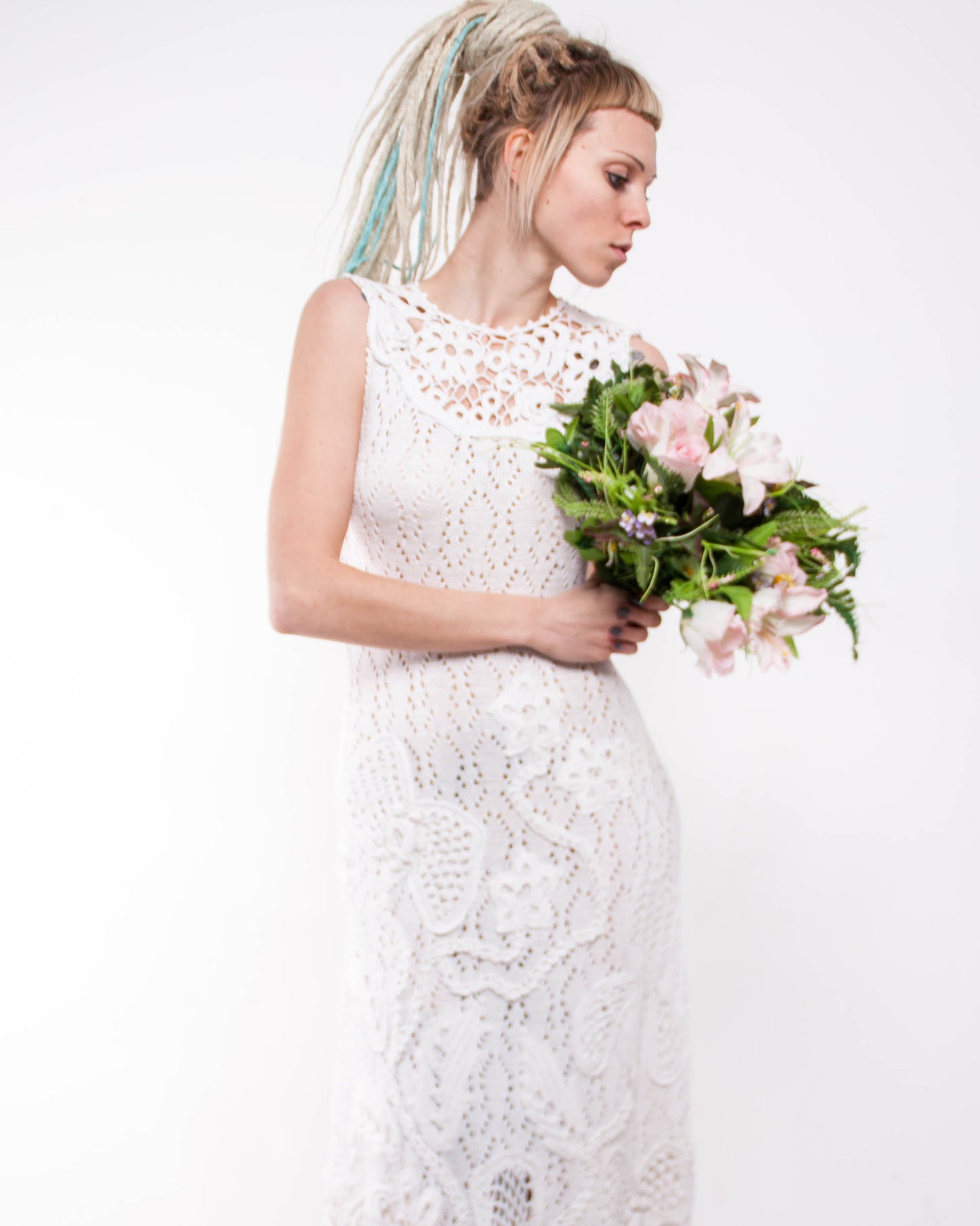 Woman in a white lace dress holding a bouquet of flowers on a white background