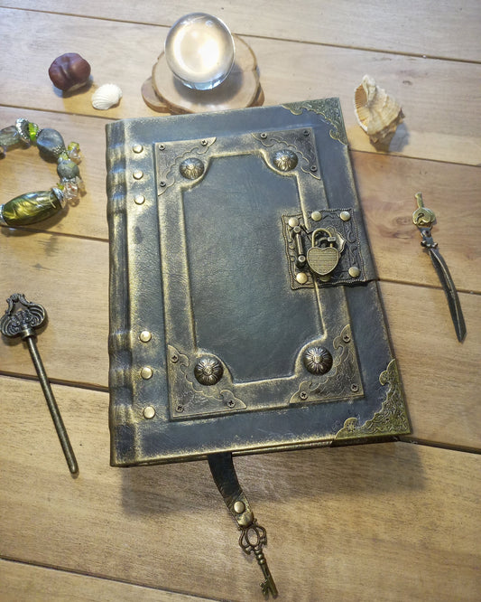 grey Aged Leather book with  Brass embelishments and keylock on a wooden surface