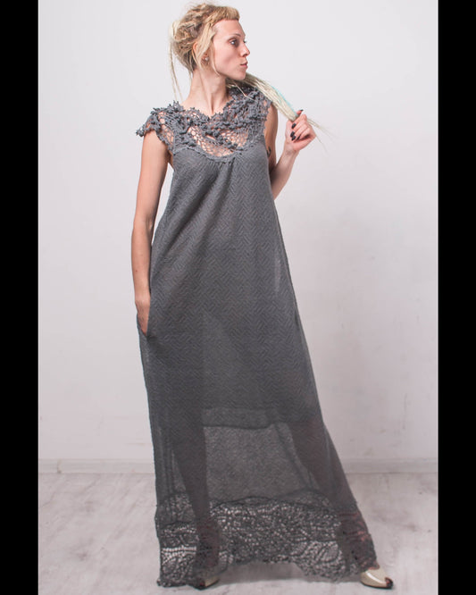 Woman wearing a long gray dress with lace details against a white background