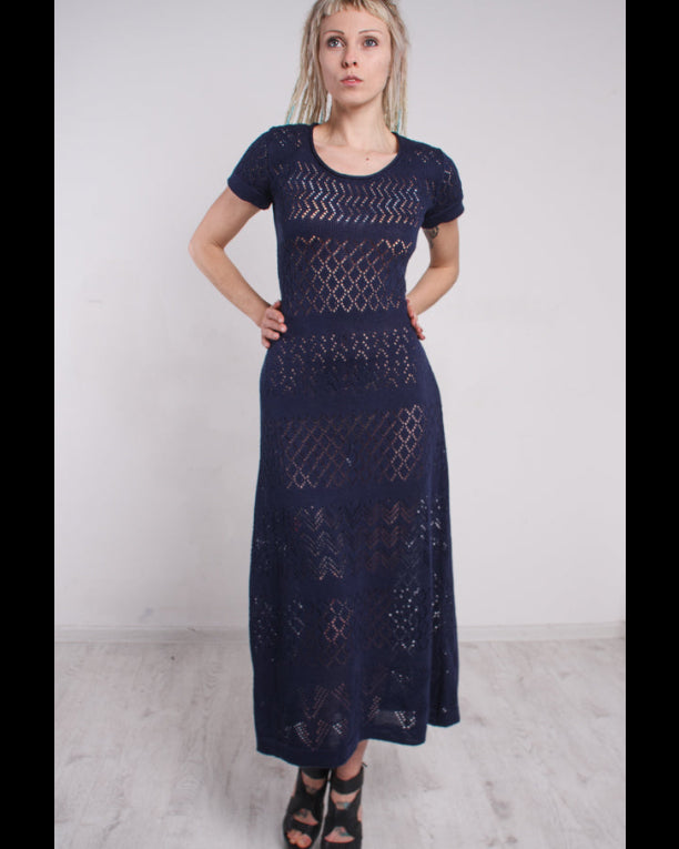 Woman wearing a navy blue lace maxi knit dress against a white background