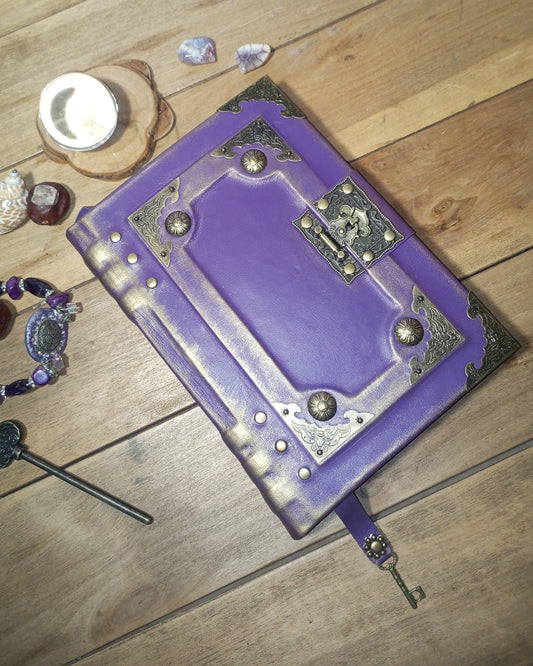 Purple leather-bound aged journal with brass embellishments on a wooden surface