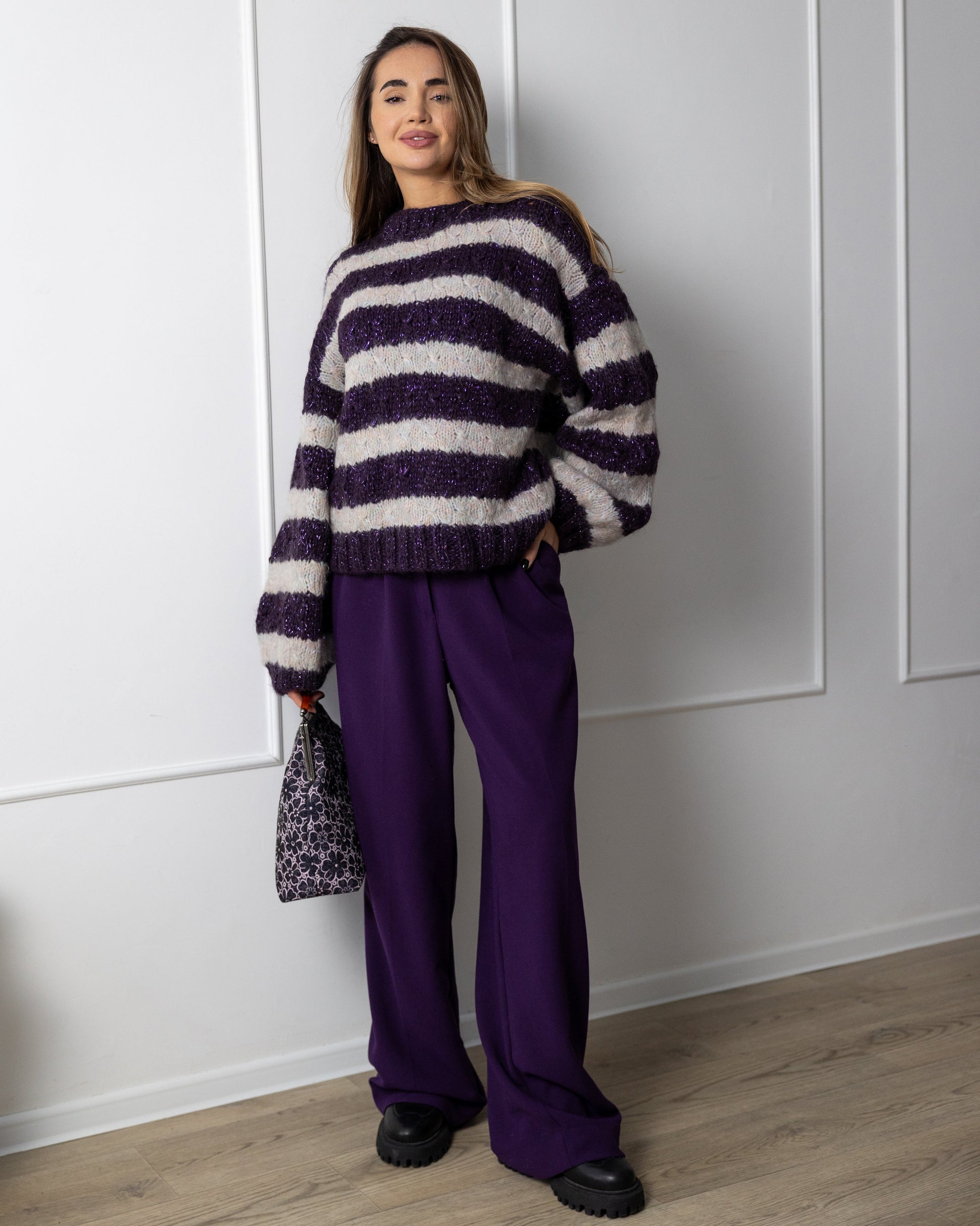 Woman wearing a purple and grey oversized mohair fluffy striped with lurex thread sweater and purple pants 