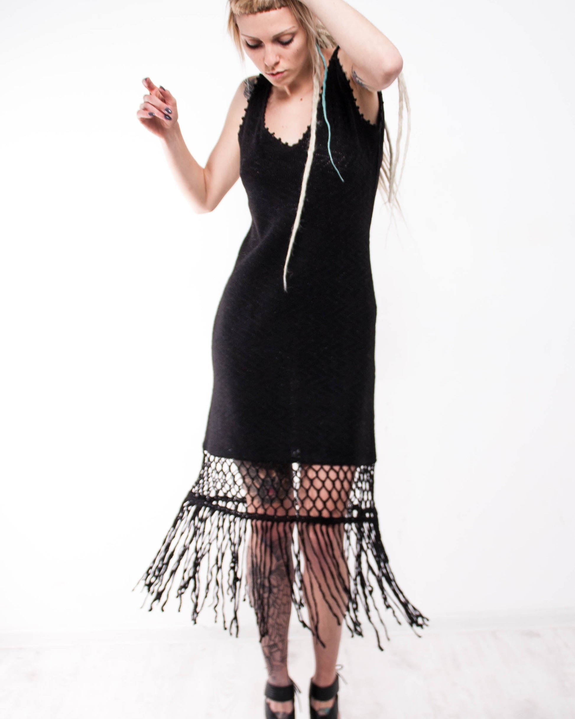 Woman wearing a mini crochet black dress with fringe details 