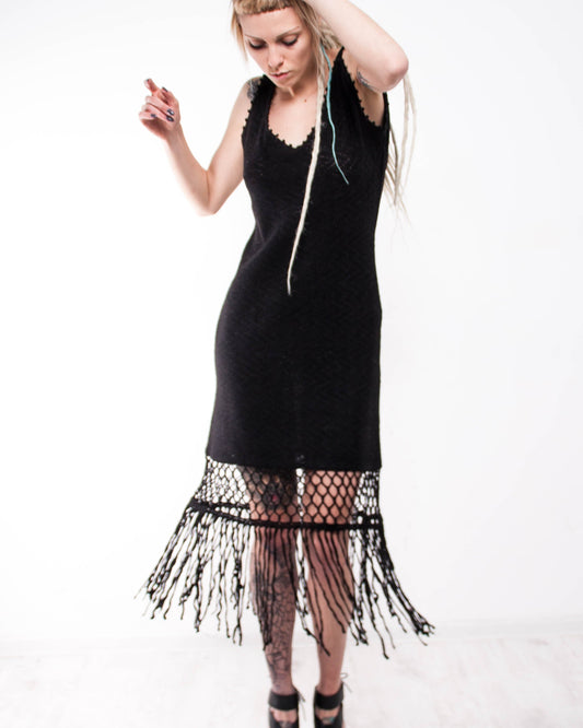 Woman wearing a mini crochet black dress with fringe details 