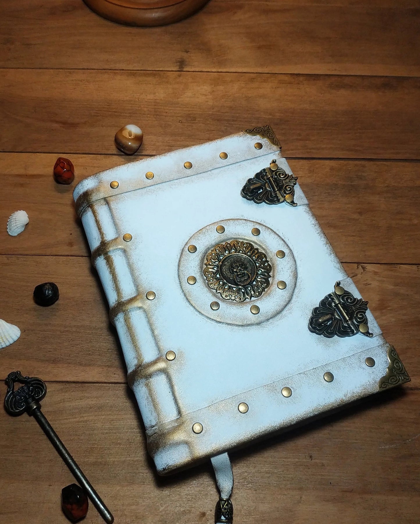 Aged leather white notebook with metal embellishments on a wooden surface 