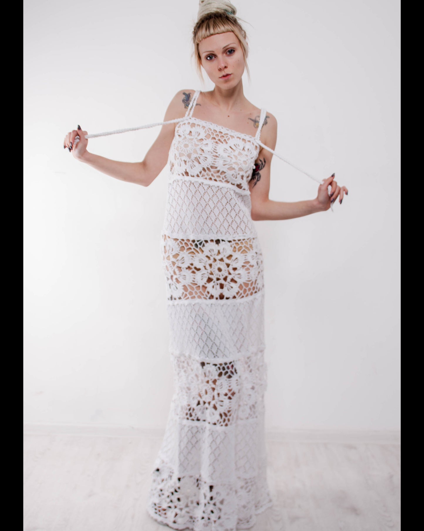 Woman wearing a crochet maxi white lace sudress against a plain background