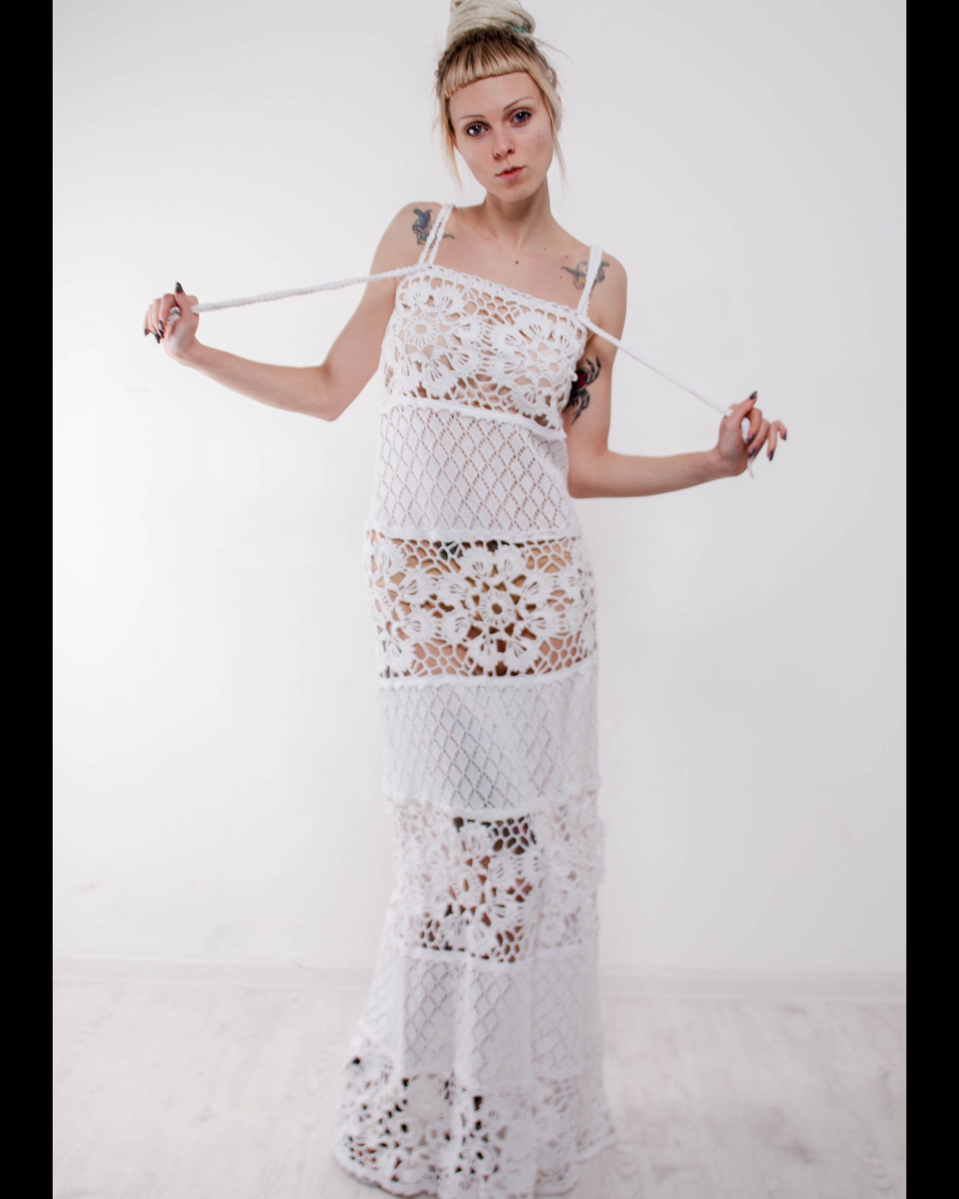 Woman wearing a crochet maxi white lace sudress against a plain background