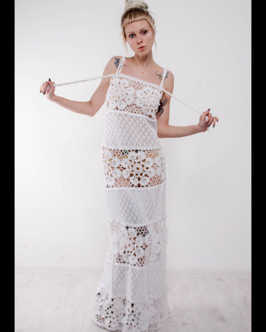Woman wearing a crochet maxi white lace sudress against a plain background